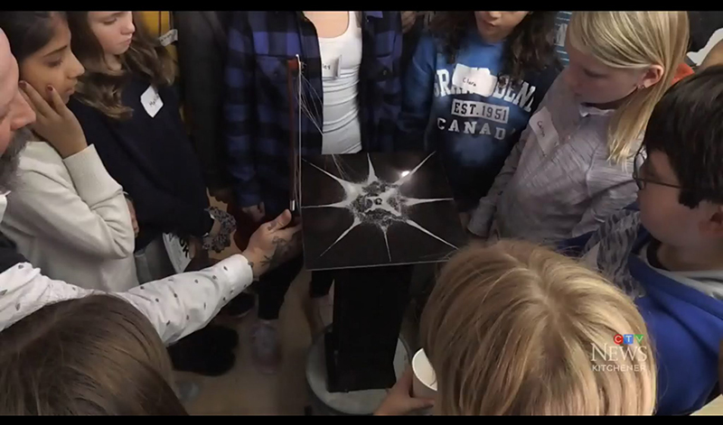 Children gathered in circle watching physics demonstration