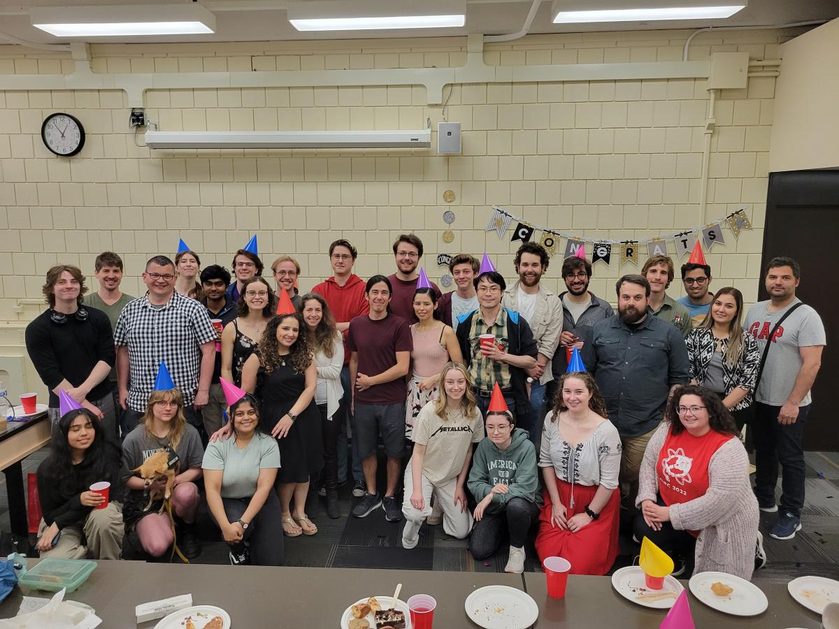 Group of students and faculty in a classroom, with party hats having a celebration.